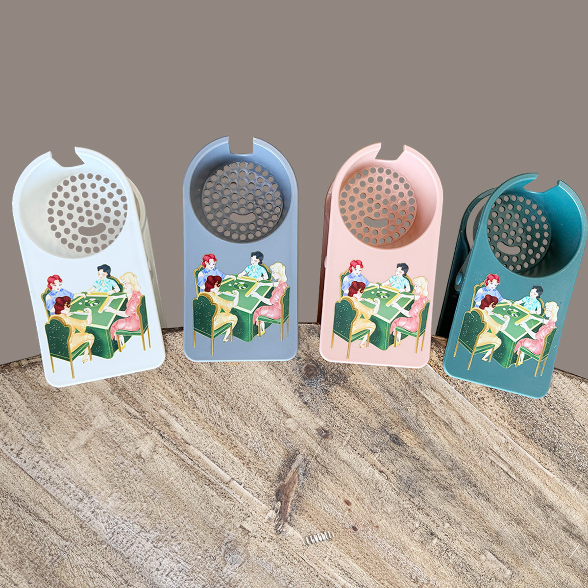 Four colorful mahjong tile holders in white, blue, pink, and teal, featuring a vintage illustration of four women playing mahjong. Each holder has a circular perforated design with a smiley face.