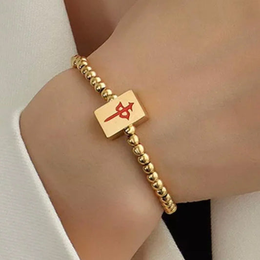 Gold-tone beaded mahjong bracelet featuring a rectangular gold tile charm with a red Chinese character symbol. Elegant mahjong-inspired jewelry shown on a wrist.
