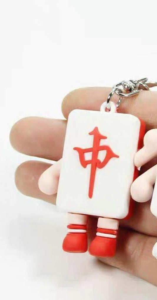 Mahjong Red Dragon tile character keychain featuring a white tile with a red Chinese character, small arms, red shoes, and a silver metal key ring, displayed in a hand.