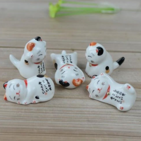 Set of five miniature white lucky cat figurines in playful sitting and lying poses, featuring black and orange markings, pink accents, and Japanese-inspired designs.