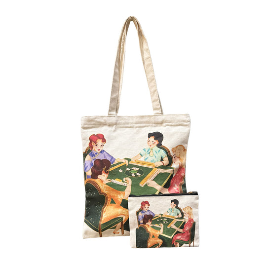Matching natural canvas mahjong tote bag and zipper pouch set featuring a colorful vintage-style illustration of four women playing mahjong around a green table. The tote has long shoulder straps, and the coordinating pouch features a black zipper.